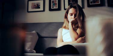 sad woman sitting on couch looking down