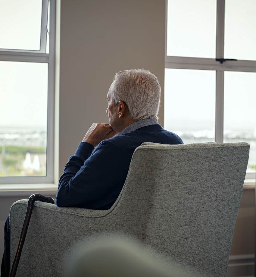 elderly man sits looking ouyt the window