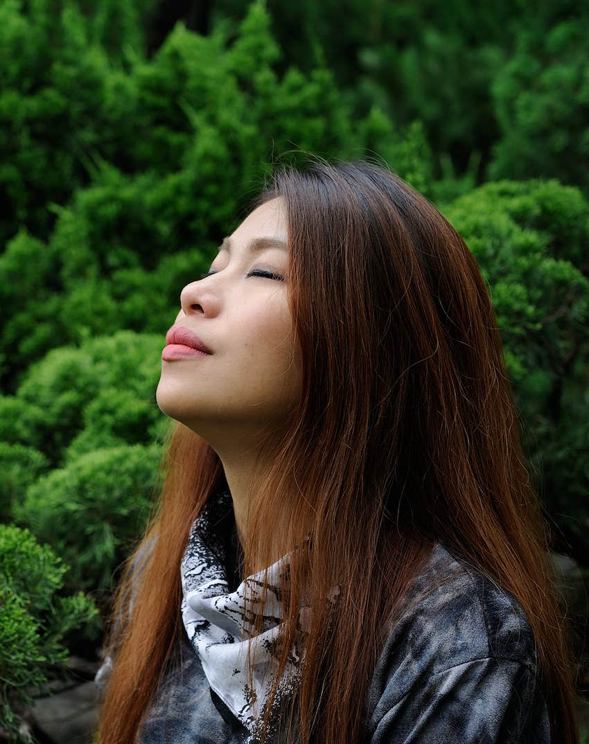 women relaxed with green background, breathing 