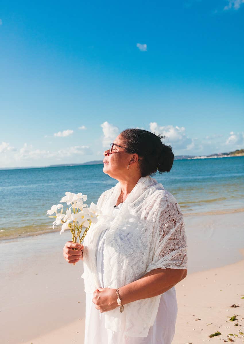 woman with flowers on beach honors her purpose