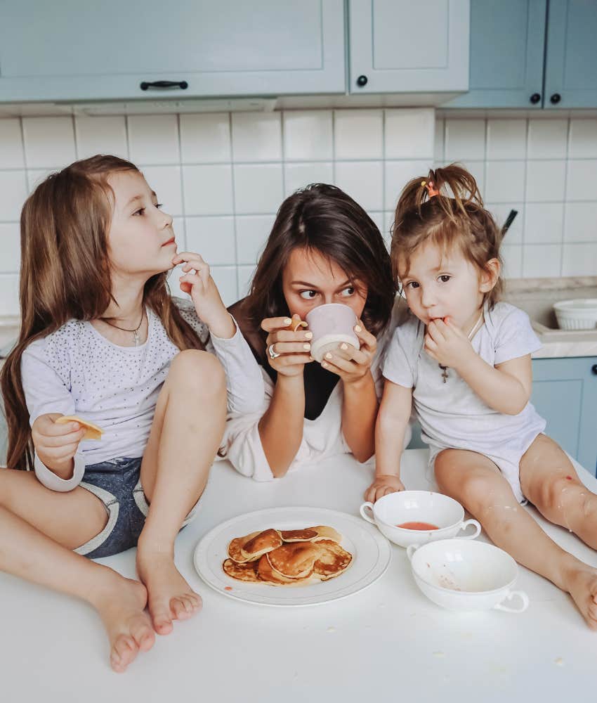 mom drinking coffee while daughters eat pancakes