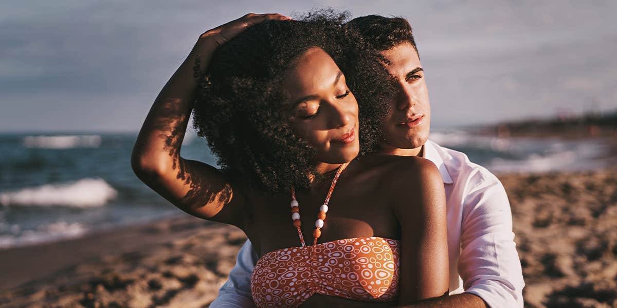 man cuddling woman on beach