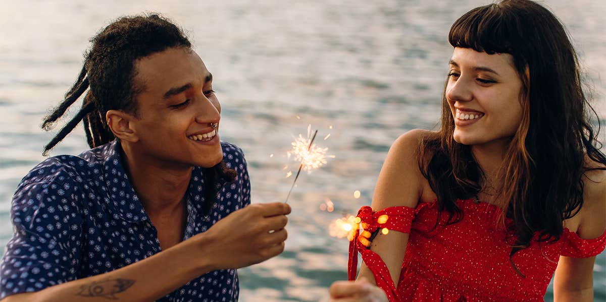 couple laughing together holding sparklers