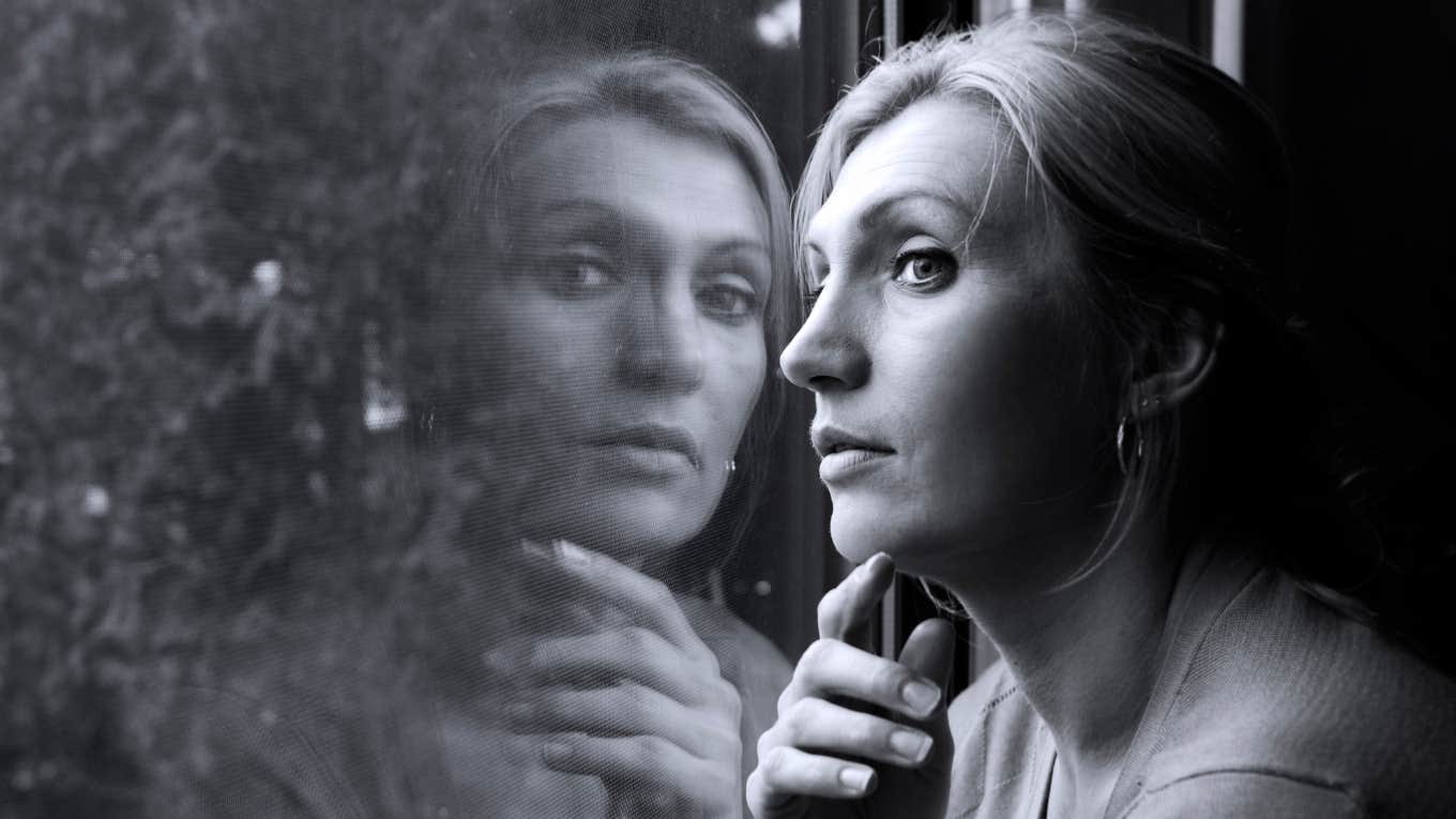 pensive woman looks out window 