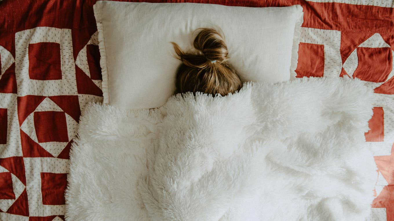woman sleeping under blanket on bed