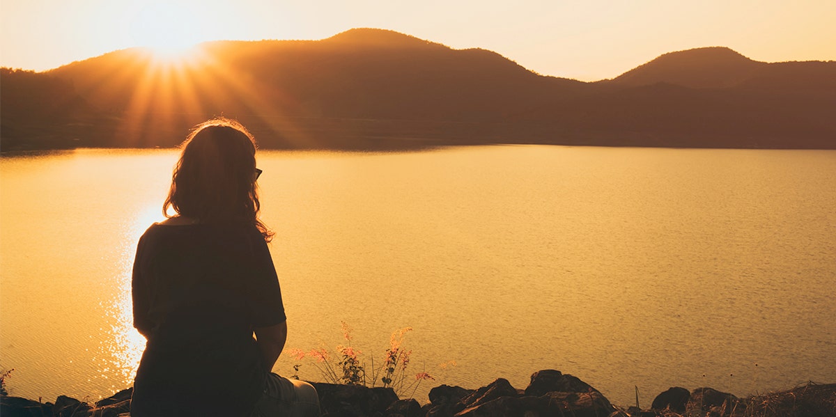 woman sitting in shadow looking at mountains