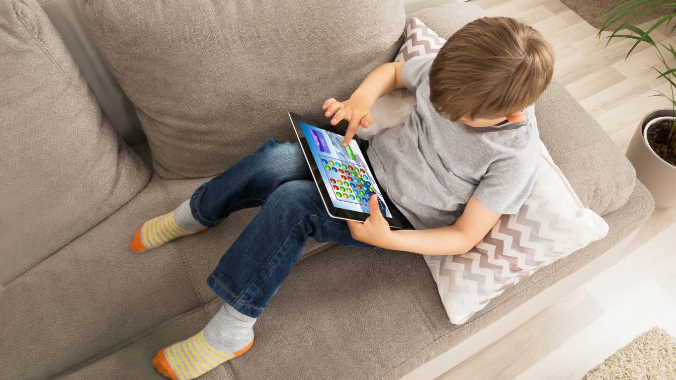 High Angle View Of Boy Using Digital Tablet For Playing Game