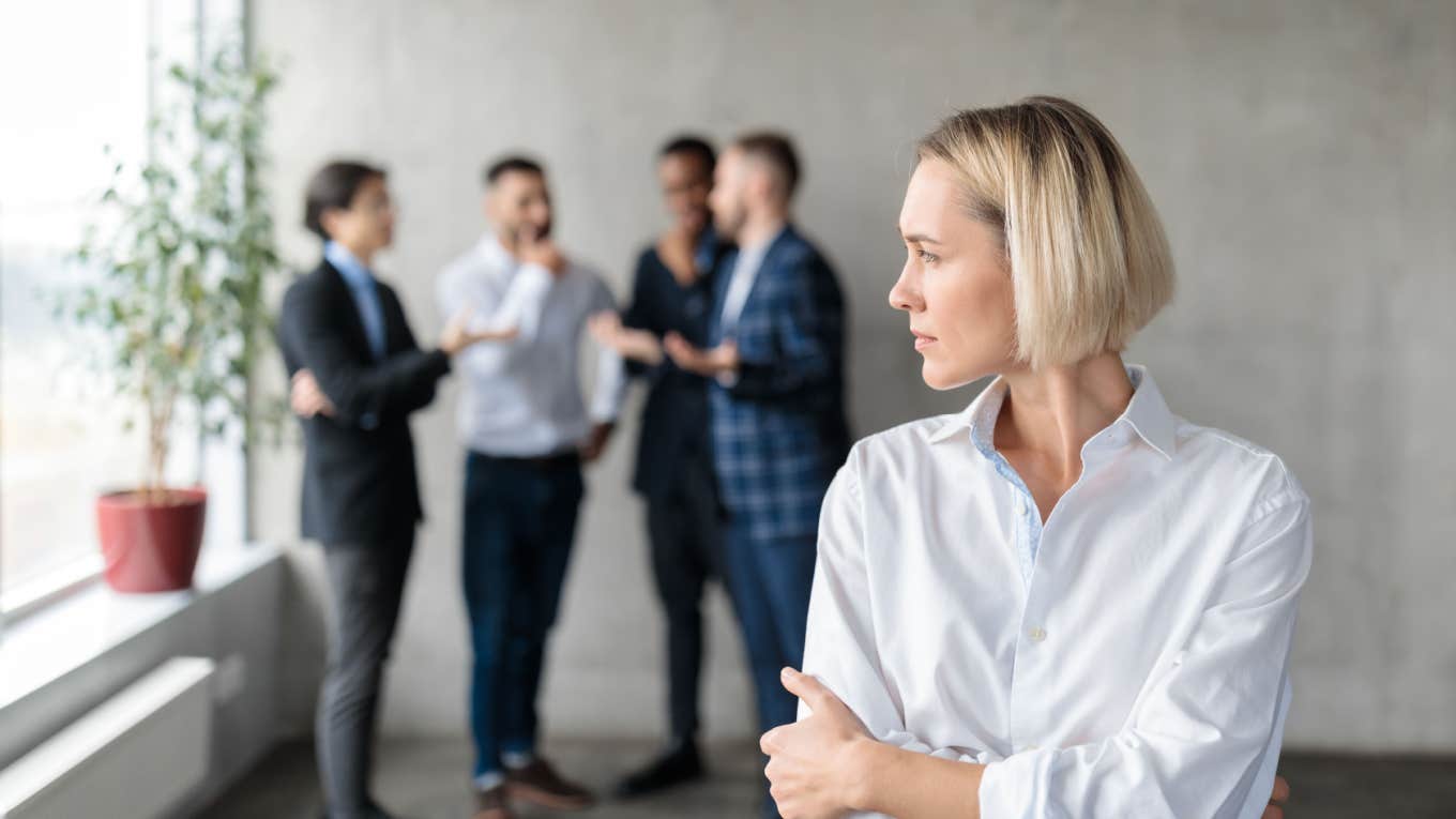 woman worries while male coworkers talk behind her back