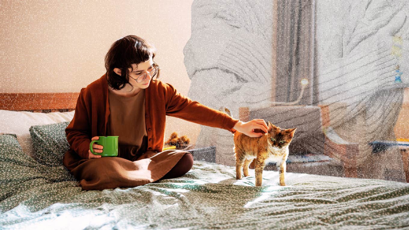 Introvert woman drinking coffee and petting her cat on her bed 
