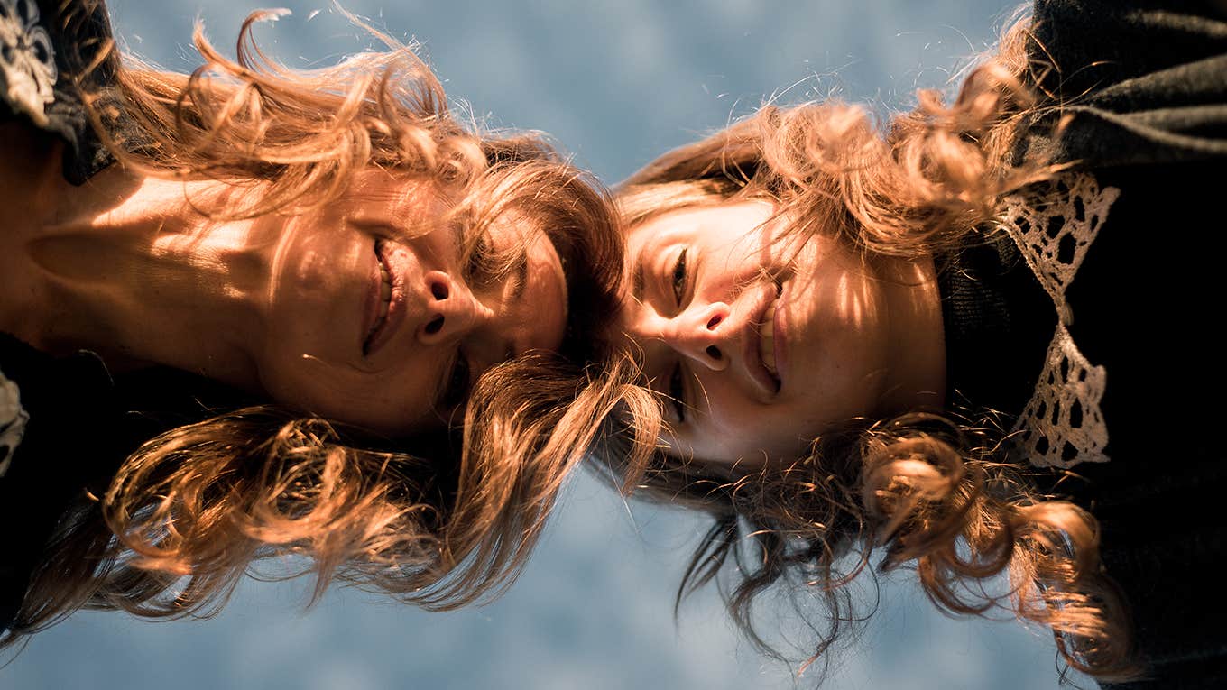 two people look down at the camera with their hair falling over their face