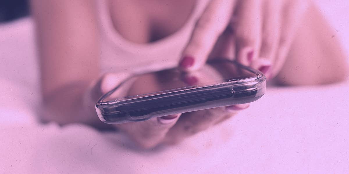 woman texting on bed