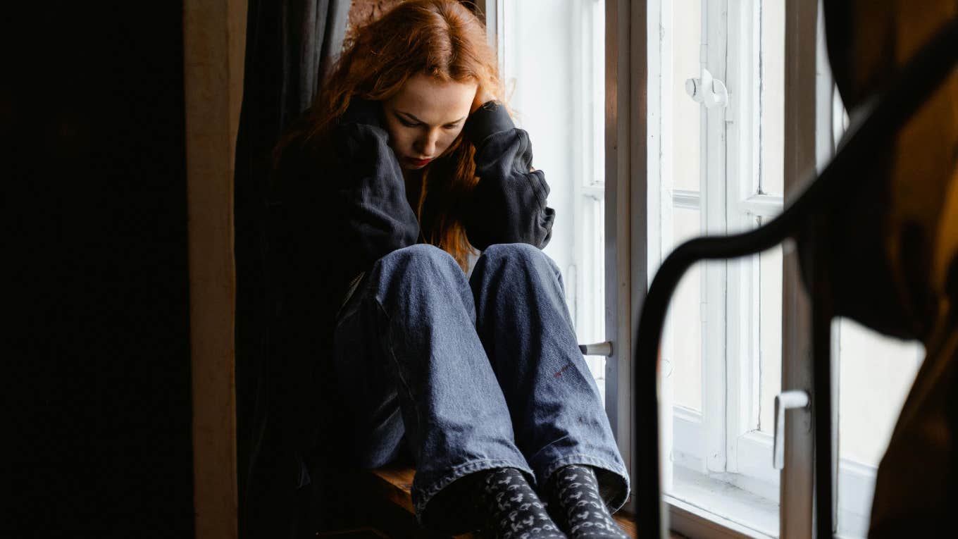 sad woman sitting at windowsill