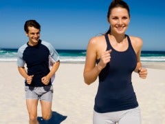 man and woman running on beach