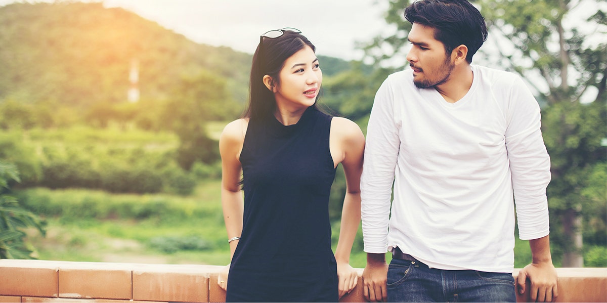 woman and man leaning against fence post