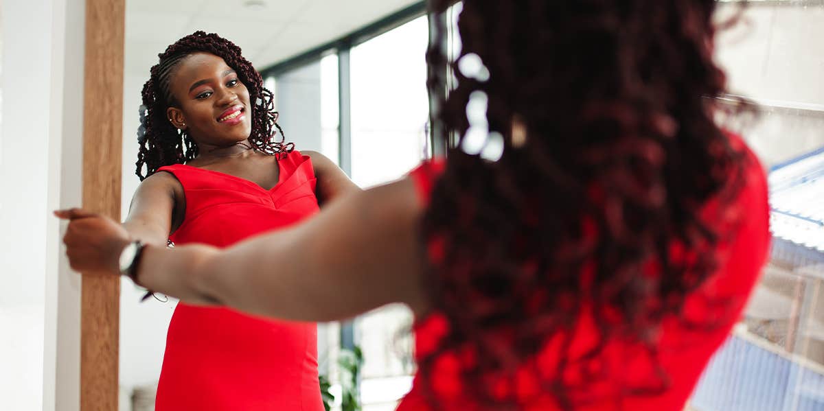 confident woman in red dress looking in mirror