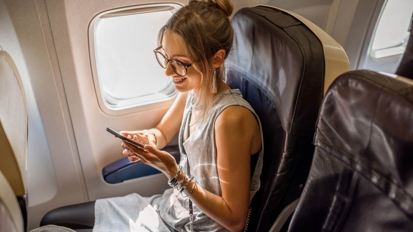 Woman texting while sitting in an airline seat. 