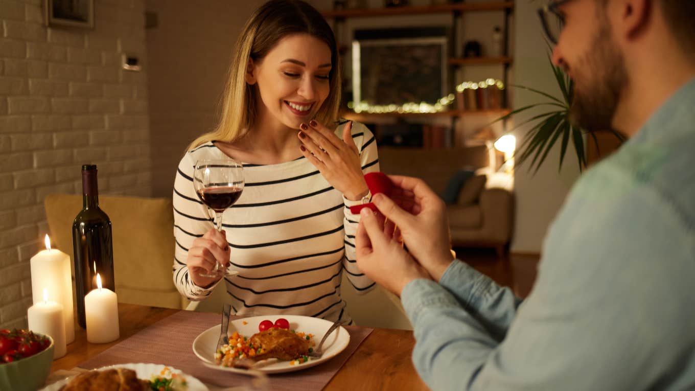 Surprised woman getting a marriage proposal over romantic dinner at home