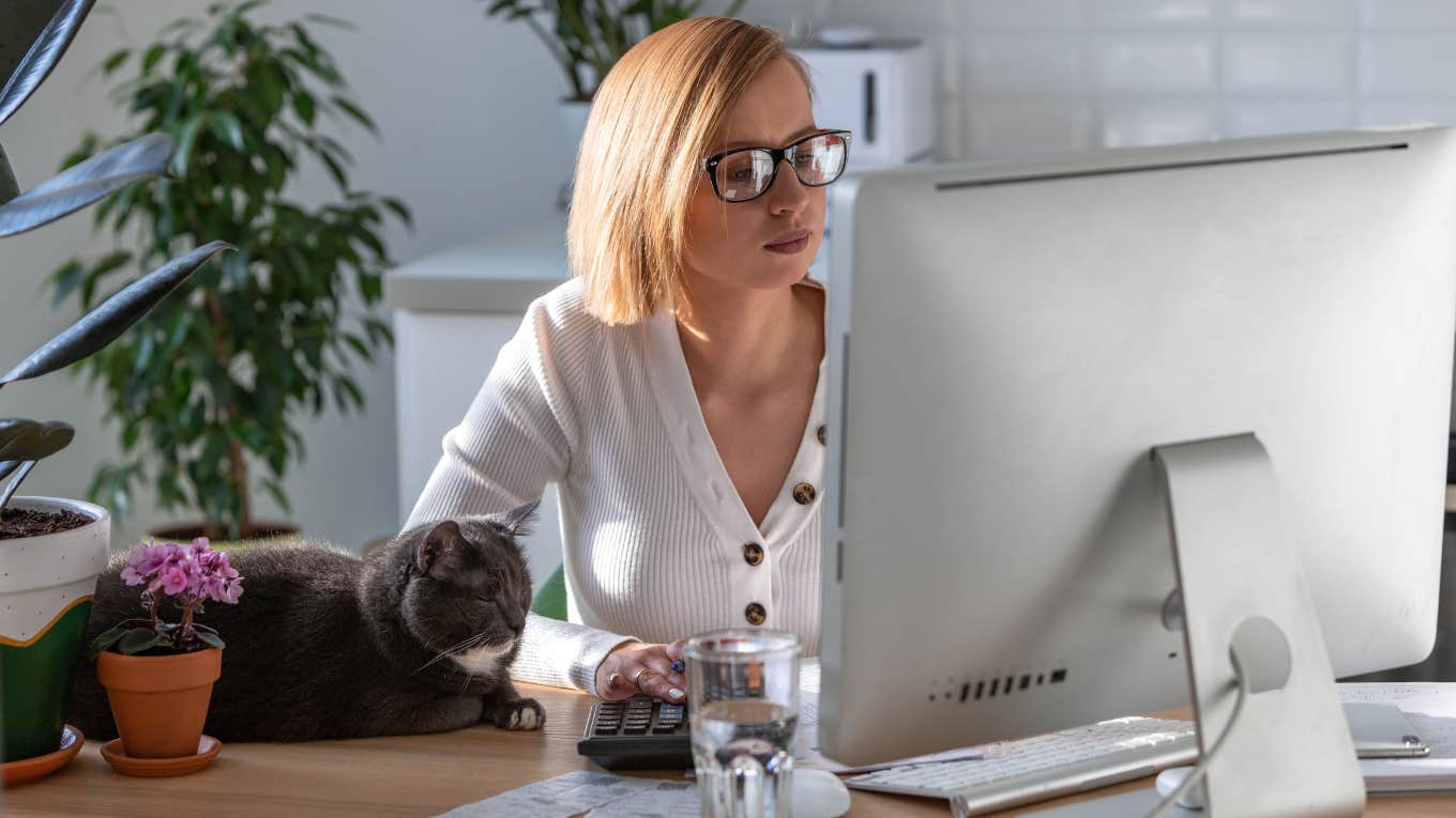 Woman working from home with a cat on her desk. 