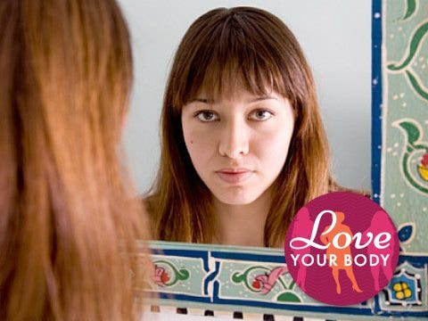 young woman with bangs looking in mirror