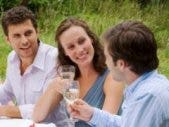 two men one woman in middle outdoor party toasting