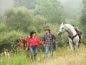 A man and a woman lead horses in a field.