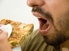 Man's mouth eating a piece of bread