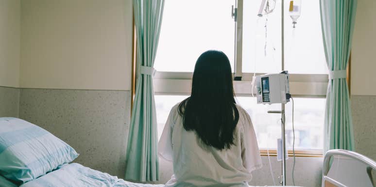 woman sitting on hospital bed looking out window