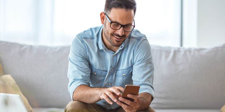 Man smiling while reading his phone. 