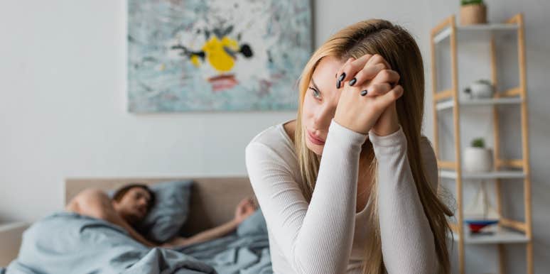 worried young woman sitting on bed after one night stand with stranger
