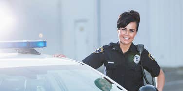 female police officer standing outside squad car