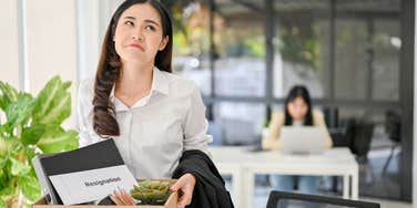 woman exiting office with box of things after quitting