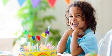 little girl smiles in front of her birthday cake at her birthday party