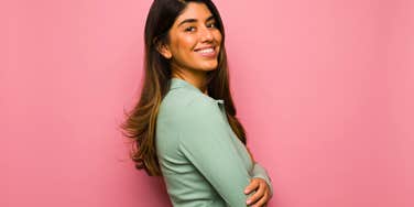secure woman smiling in front of pink background