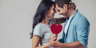 couple hugging while paper holding heart
