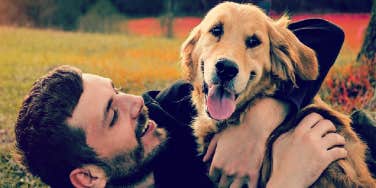 man hugging dog smiling