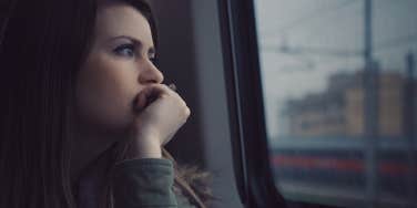 Woman looking out window sad 