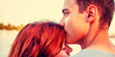 Handsome young man kissing the top of his girlfriend's head