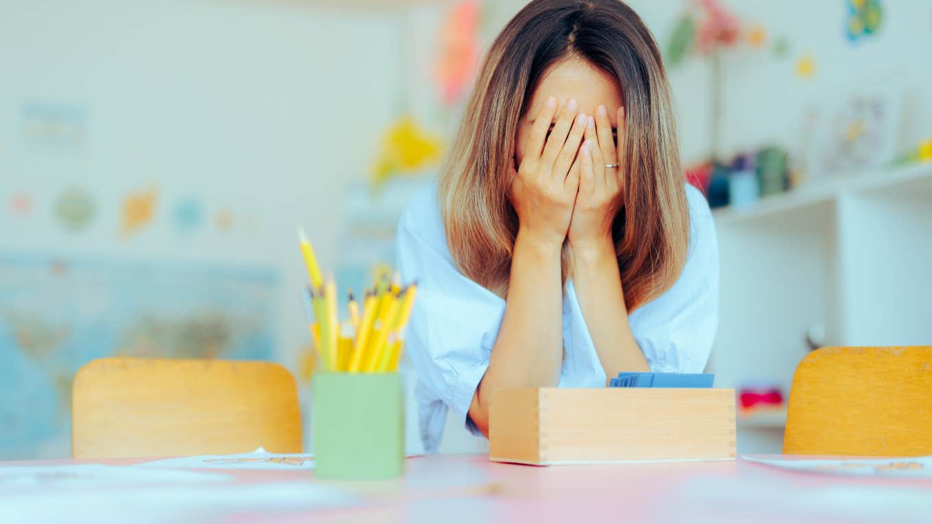 Teacher Worries ‘School Refusal’ Is Becoming A Problem In Young Students frustrated teacher sitting at desk with head in hands