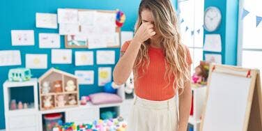 Teacher frustrated pinching nose in classroom.