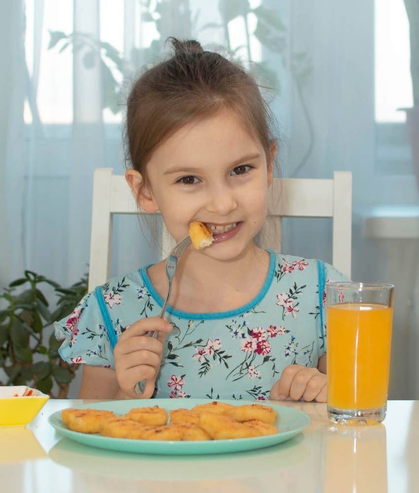 little girl happily eating fast food nuggets