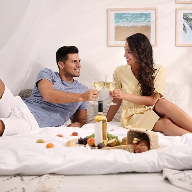 couple toasting with wine in bed