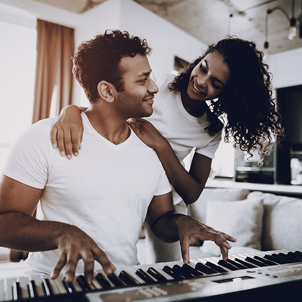 man playing piano with woman standing behind him