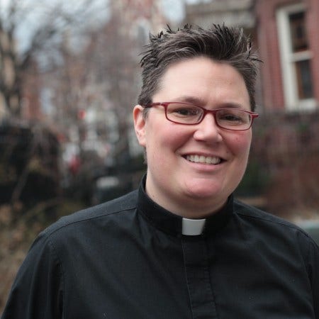 Rev. Kansfield, a white woman with very short brown hair and glasses, in clerical collar