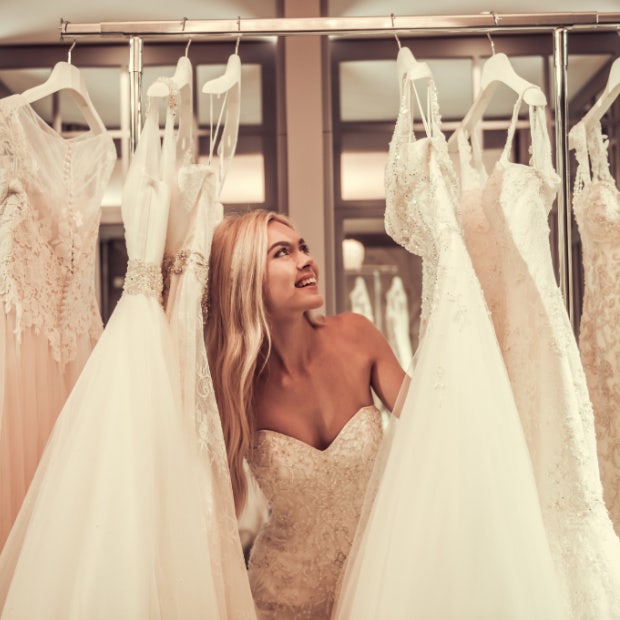 bride looking at wedding dresses on a rack