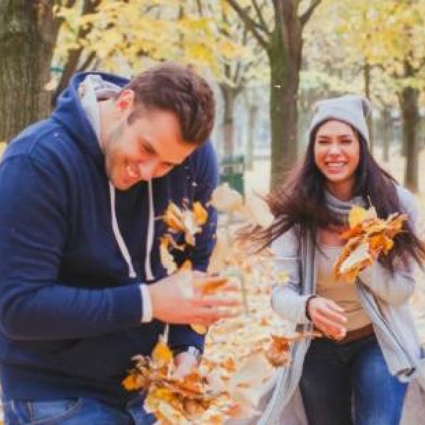 couple playing with fall leaves during cuffing season
