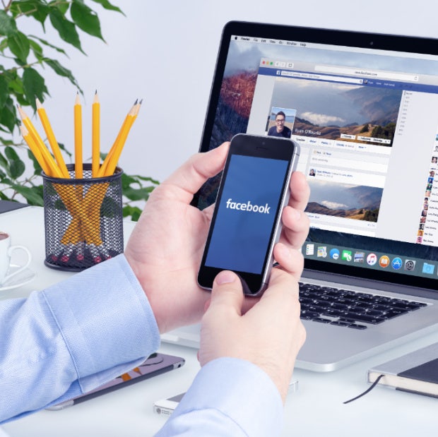 man with facebook on his phone and computer