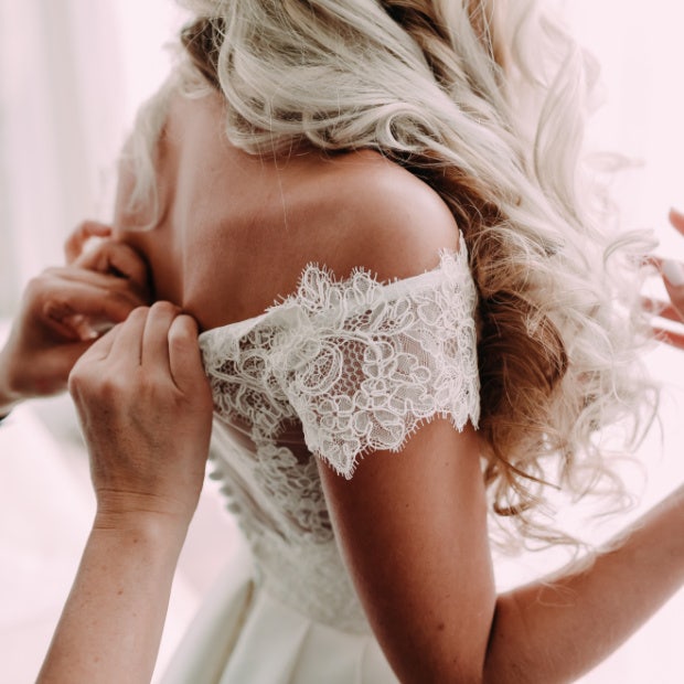 woman getting the back of her wedding dress buttoned