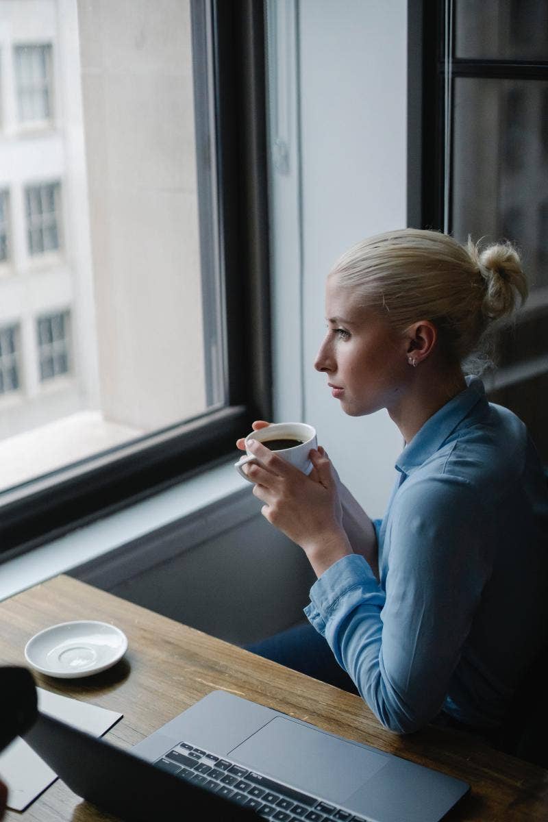 businesswoman holding a coffee mug looking out the window