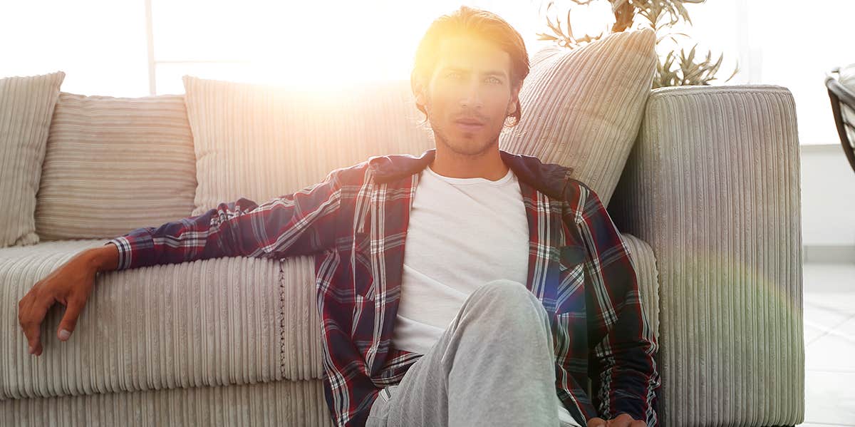 confident guy sitting on the carpet in a cozy living room.