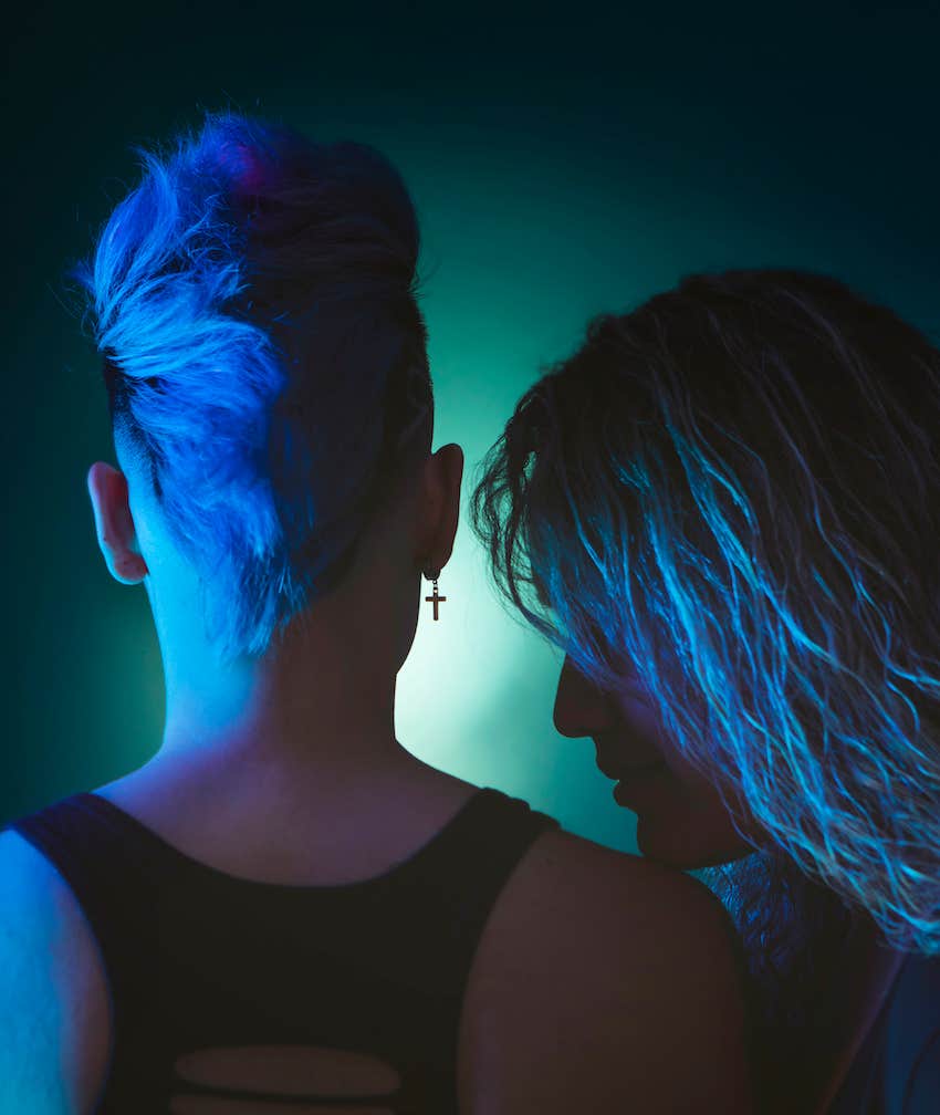 blue light couple one rests chin on others shoulder